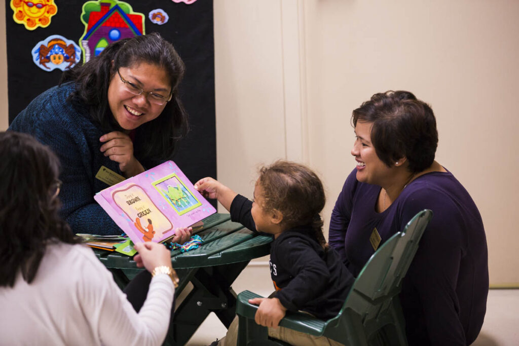 Smiling daycare worker looking at a book with a child