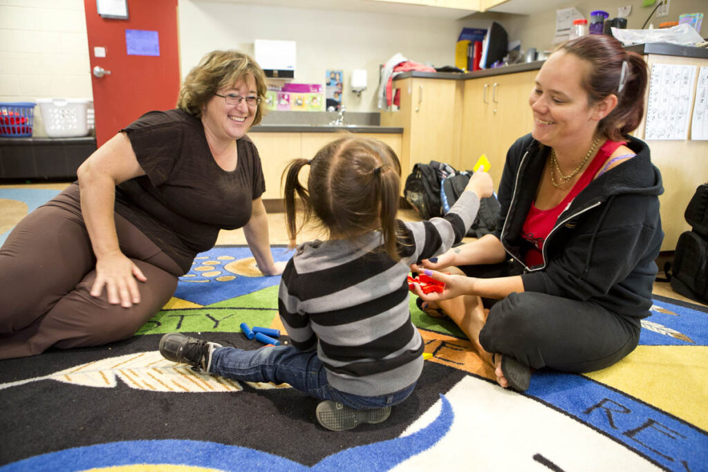 Two daycare workers playing with child at daycare