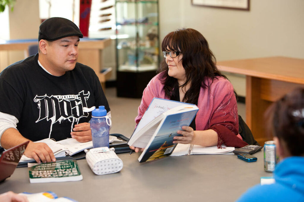 People sitting at a table reading a textbook