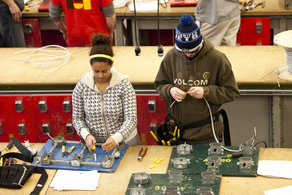 Electrical students in a workshop learning how to wire on training boards