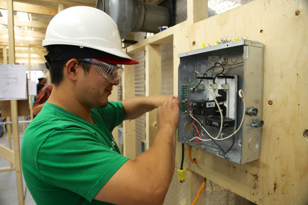 Electrical student in training construction site wiring a box