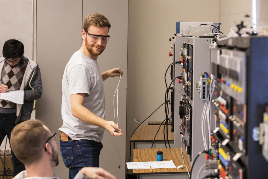 Student in a lab holding some cables and ready to plug them into a device