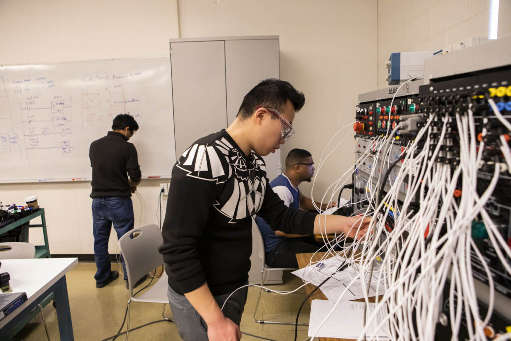 Electrical engineering student plugging cables into a device in a lab