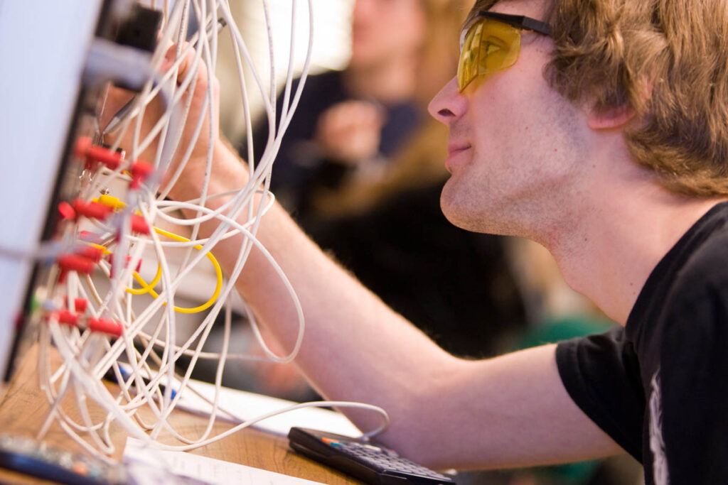 Electrical engineering student plugging cables into a device in a lab