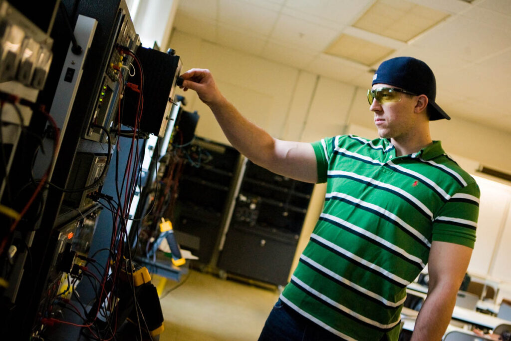 Electrical engineering student plugging cables into a device in a lab