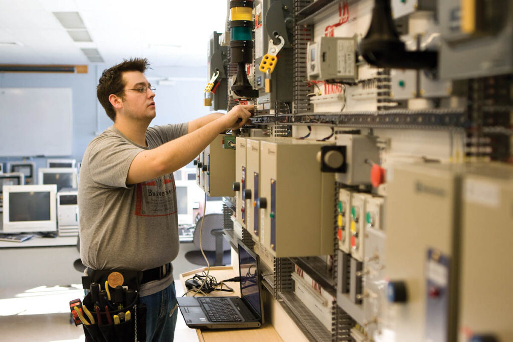 Electrical engineering student plugging cables into a device in a lab