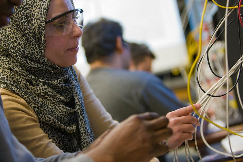 Electrical engineering student plugging cables into device