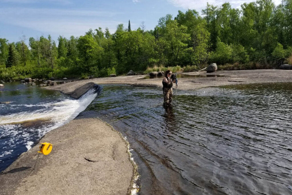 Person measuring water levels in stream