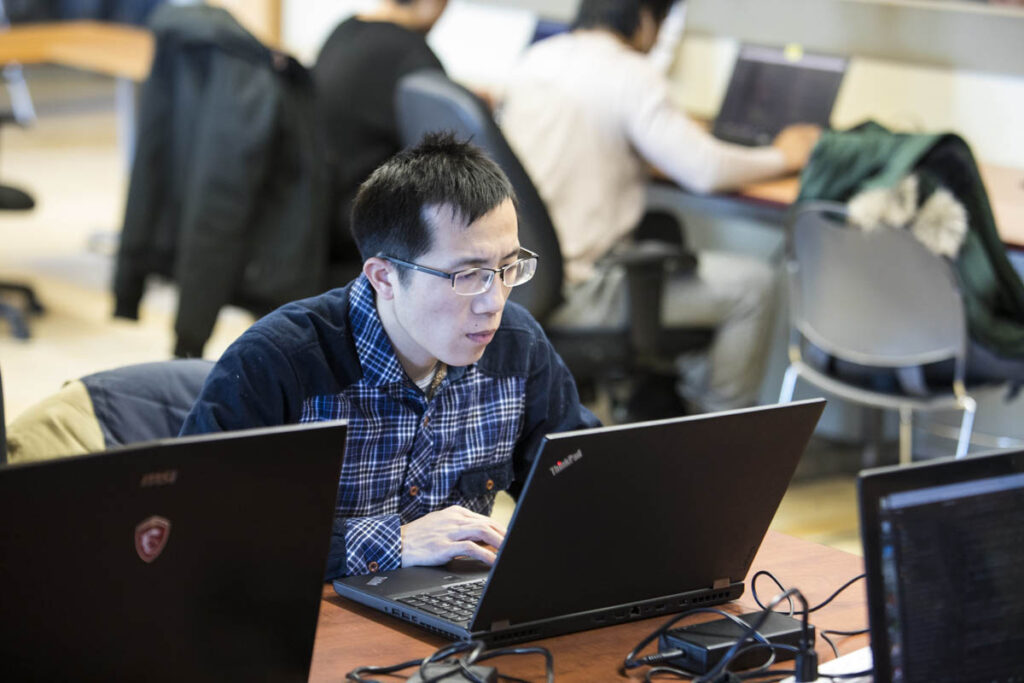 Man in classroom working on laptop