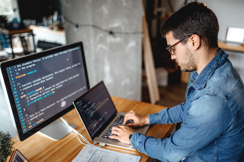 Man coding on a laptop in an open office