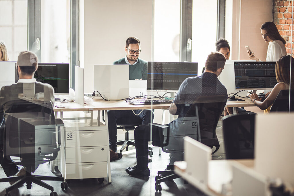 Group of employees coding in an open office floor plan