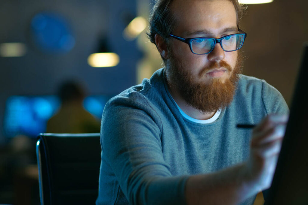 Man drawing on a tablet in a dimly lit room