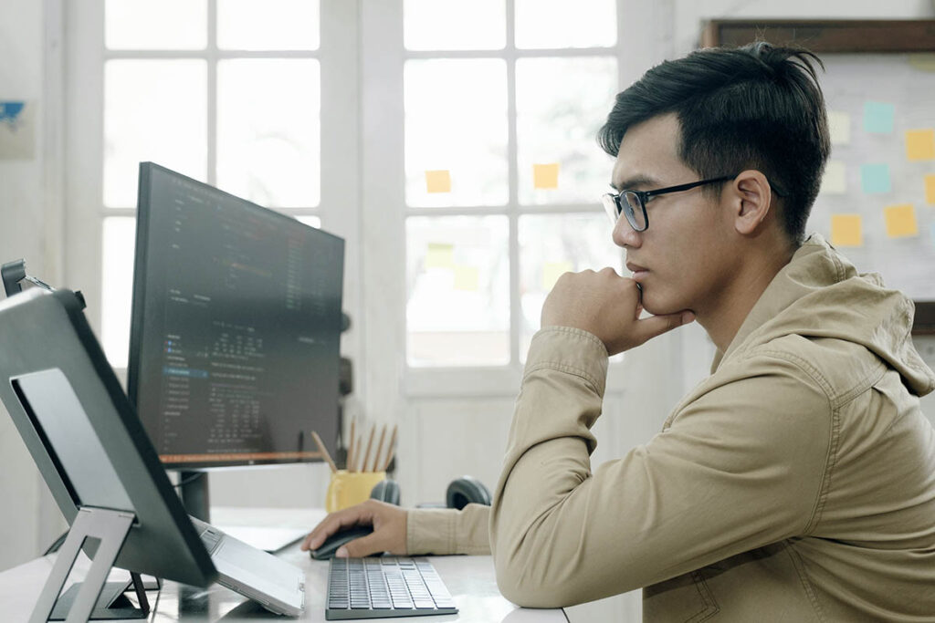 Guy sitting at a computer with a dual monitor set up