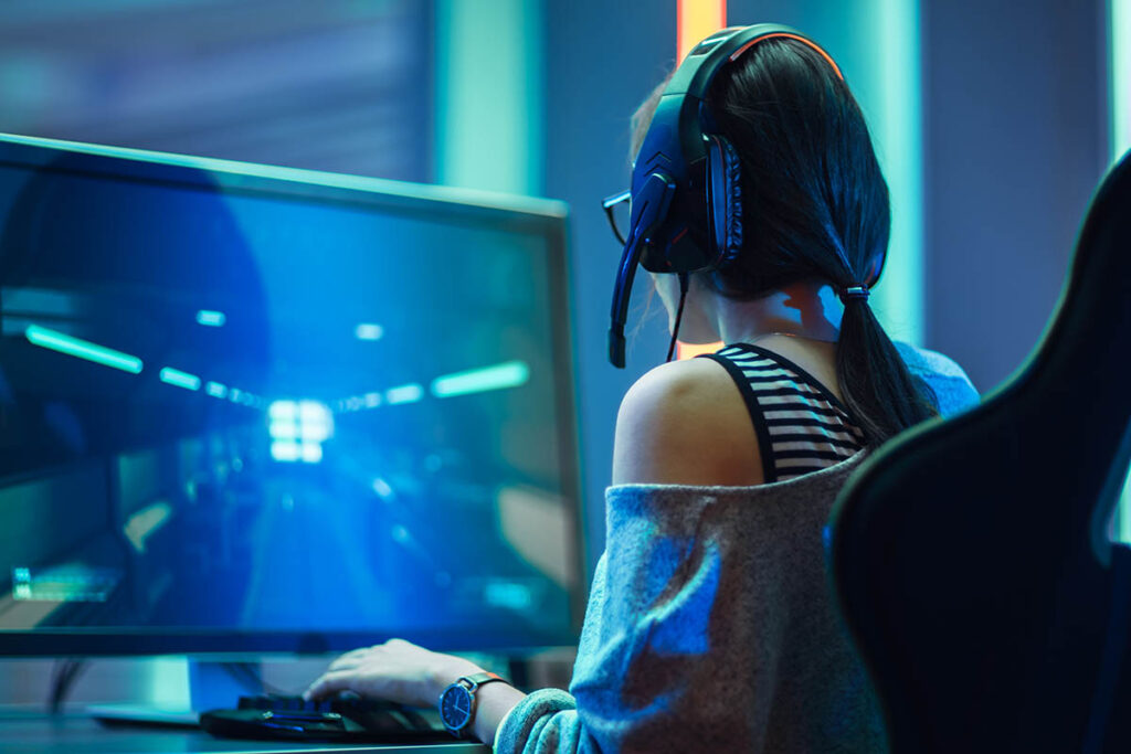 Person wearing headphones playing a game on a large computer screen