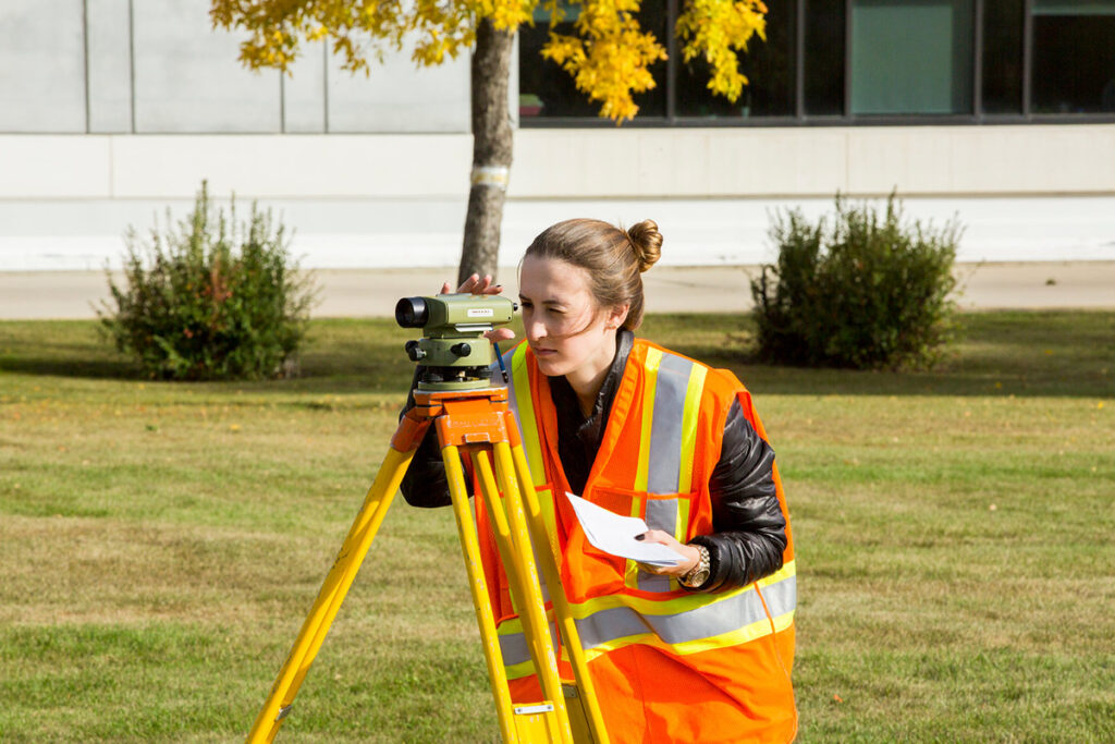 Student learning how to use surveying equipment outdoors