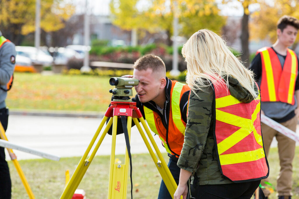 Students learning how to use surveying equipment outdoors