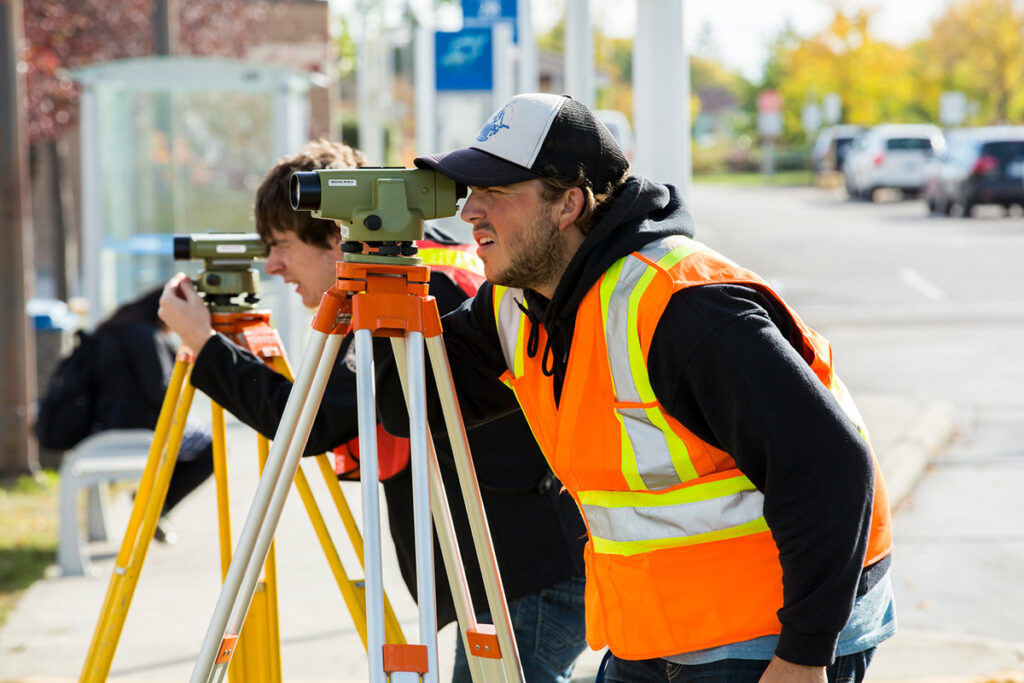 Students learning how to use surveying equipment outdoors