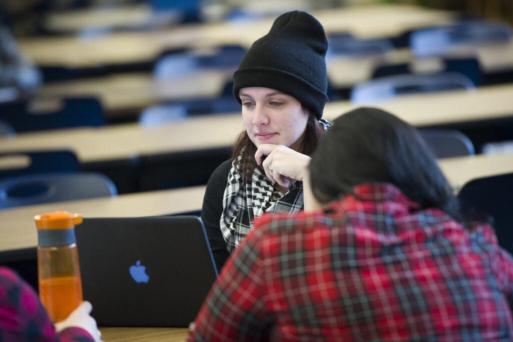 Students in an open workspace working on laptops