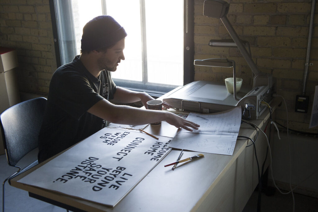 Designer at a desk creating artwork with hand-drawn typefaces