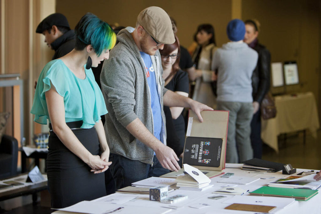 People looking through art at a large art show