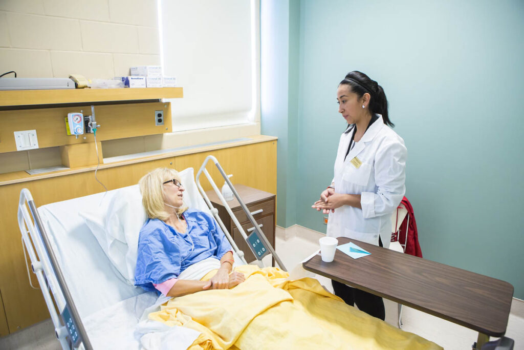 Health care aide talking to patient in hospital bed