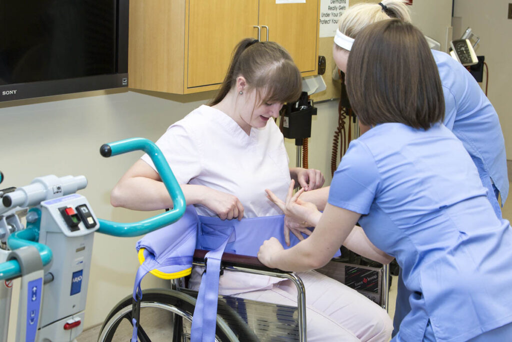 Health care aides assisting patient in wheelchair