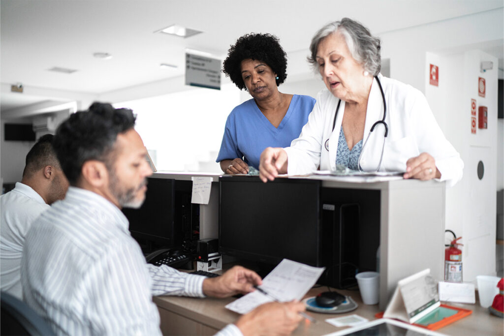 Nurse and doctor talking to health unit clerk at hospital