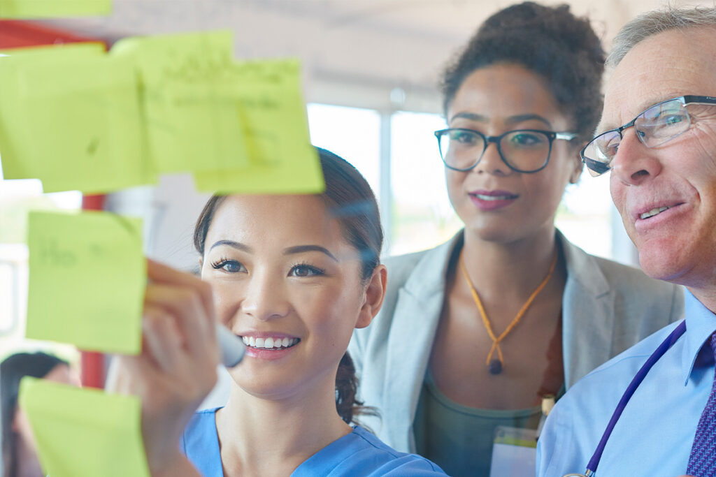 Medical professionals looking at sticky notes on window