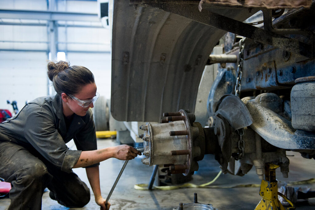 Mechanic student working on the axel of a large vehicle in a shop