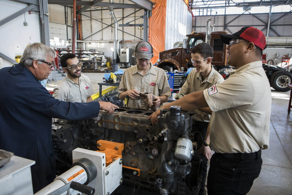 Instructor teaching students how to work on a vehicle engine