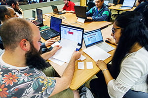 People sitting around a table with laptops