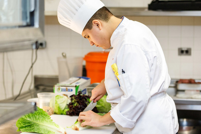 Chef cutting lettuce in a kitchen
