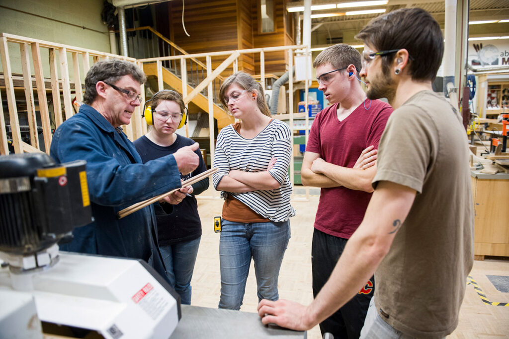 Instructor showing students some wood in a woods shop