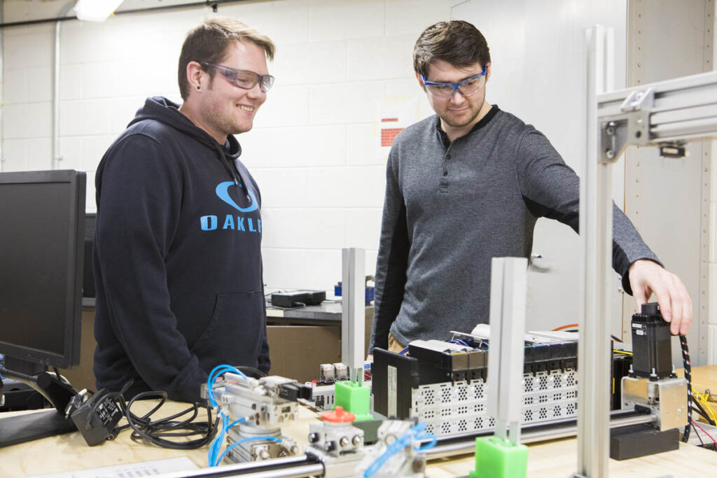Two students talking in a lab working with some electronic controls