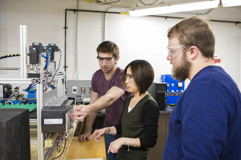 Instructor showing two students how to control some electronics in a student lab