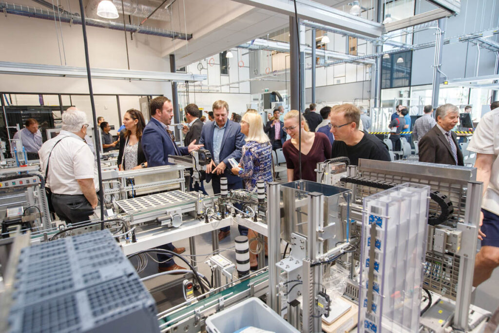 People at an industry event milling around a robotics laboratory
