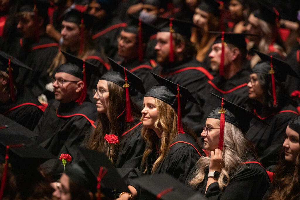 Graduates wearing caps and gowns ni the audience at convocation