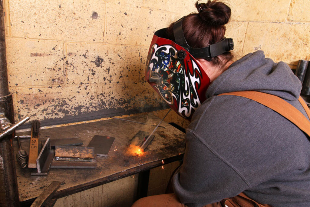 Welding student working on a piece of metal in a welding lab