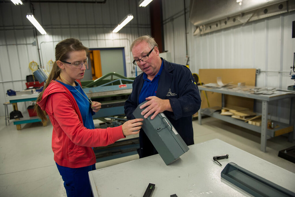 Instructor holding a toolbox and talking to a student