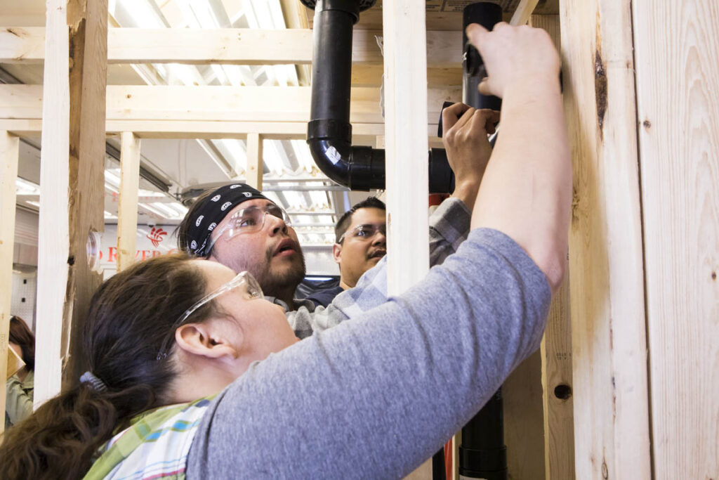 Students fitting pipes into the frame of a simulated construction site