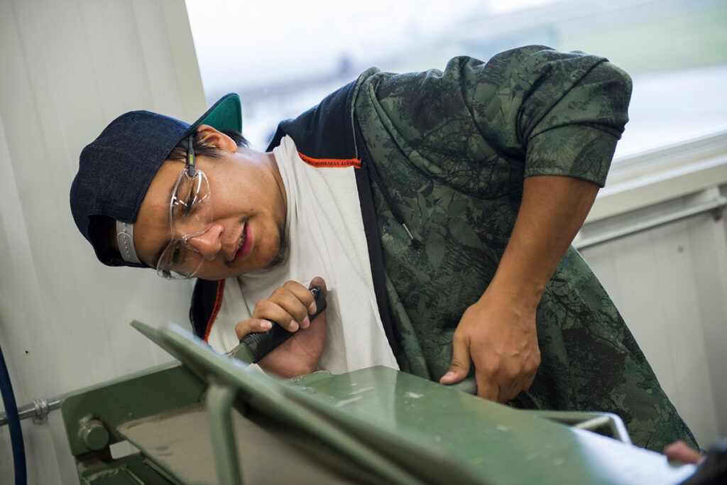 Student wearing safety glasses in a shop working with a large machine