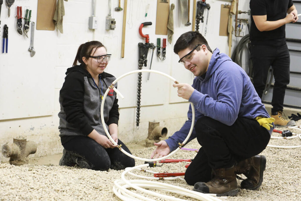 Trades instructor showing student how to connect pipes together