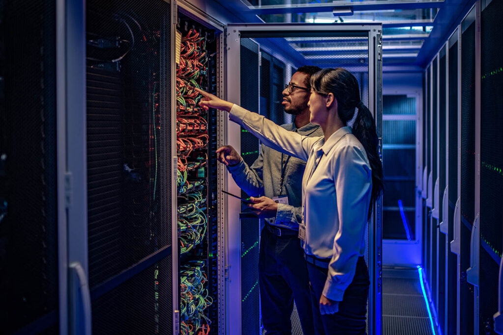 Man and woman in a networking room plugging in networking cable