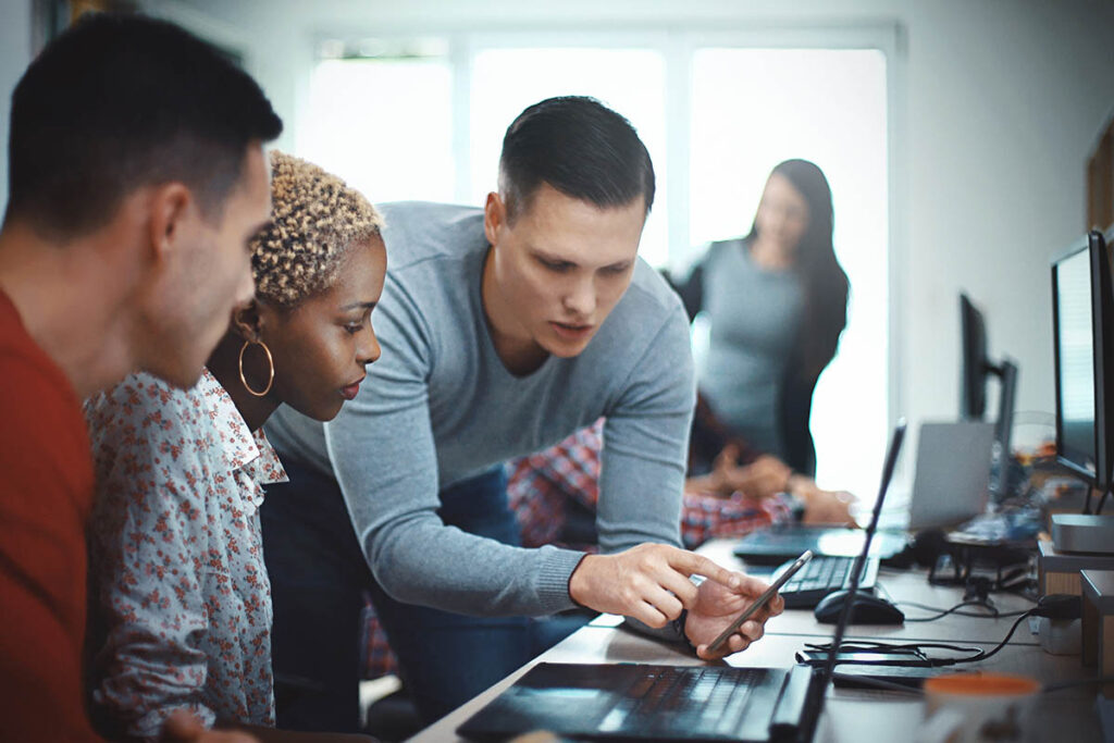 Instructor showing students something on a laptop screen in a classroom