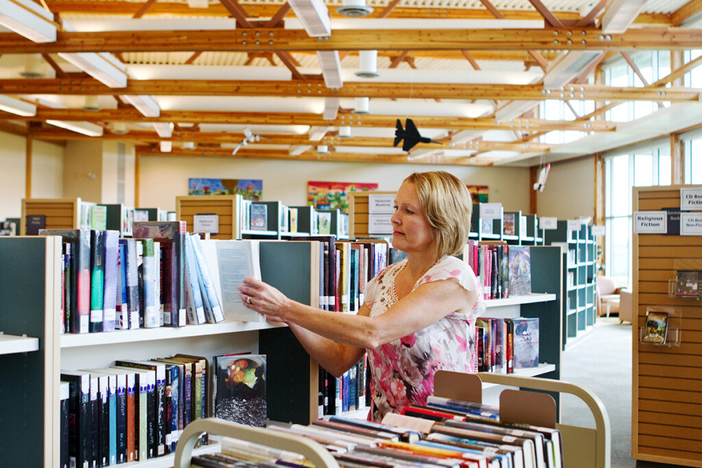 Librarian putting books on shelf in a library