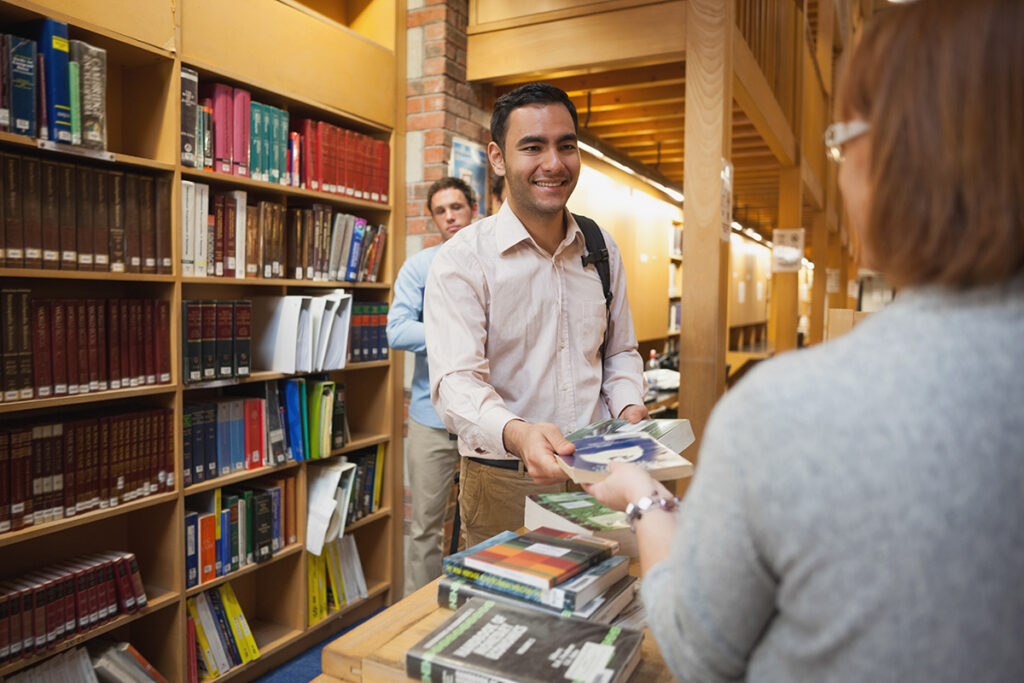 Man checking out books from a library