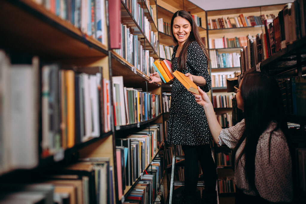 Librarian putting books on bookshelf in library