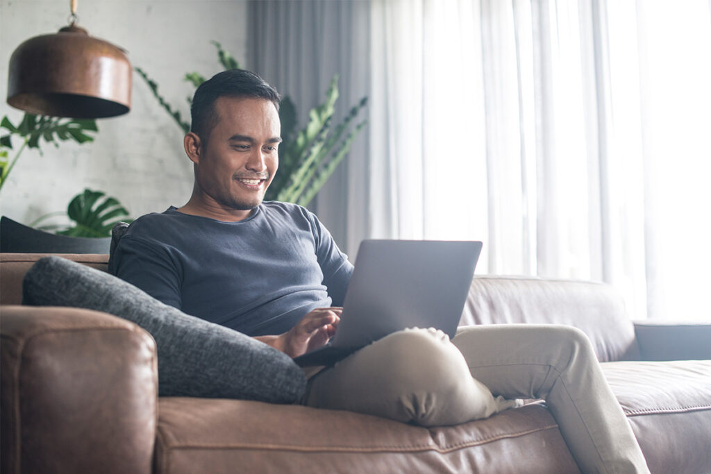 Man using a laptop on a comfortable chair