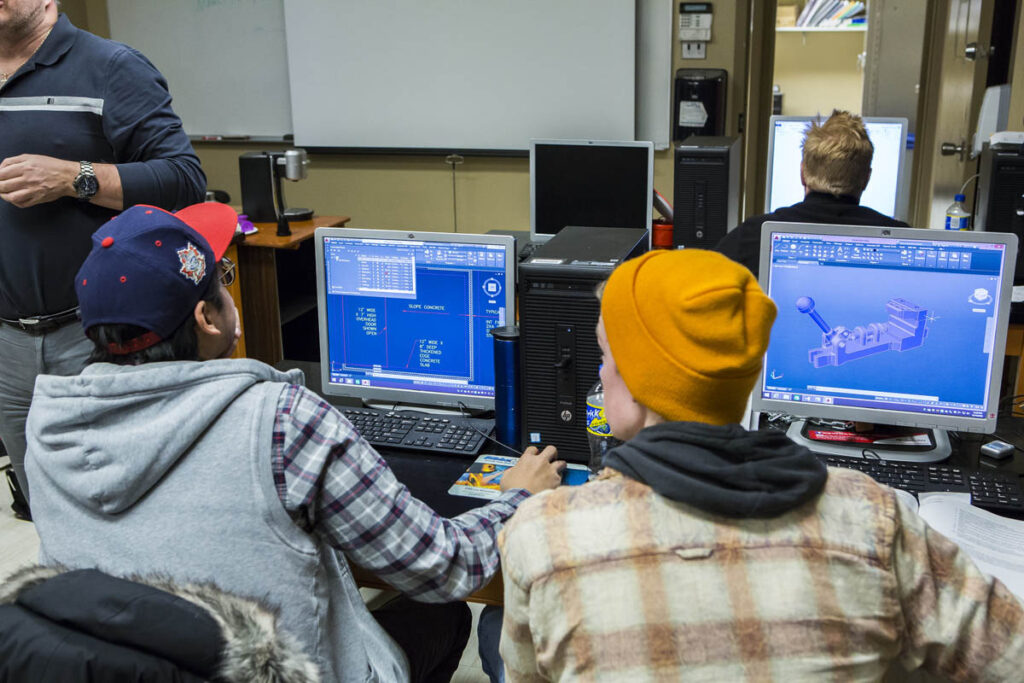 Students looking at CAD drawings on a computer screen in a computer lab