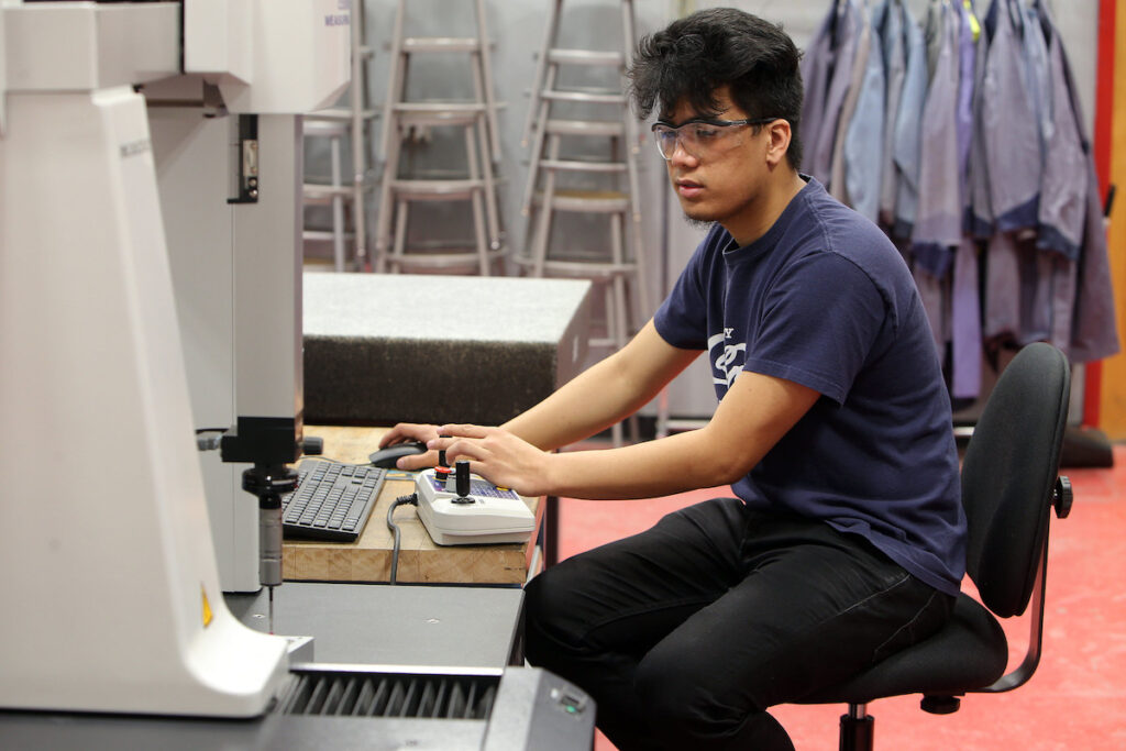 Student operating advanced manufacturing equipment in a lab
